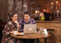 Wizytówka Google - Para pracuje przy laptopie w kawiarni, a w tle widać bar i obsługę – scenka związana z promocją lokalnego biznesu